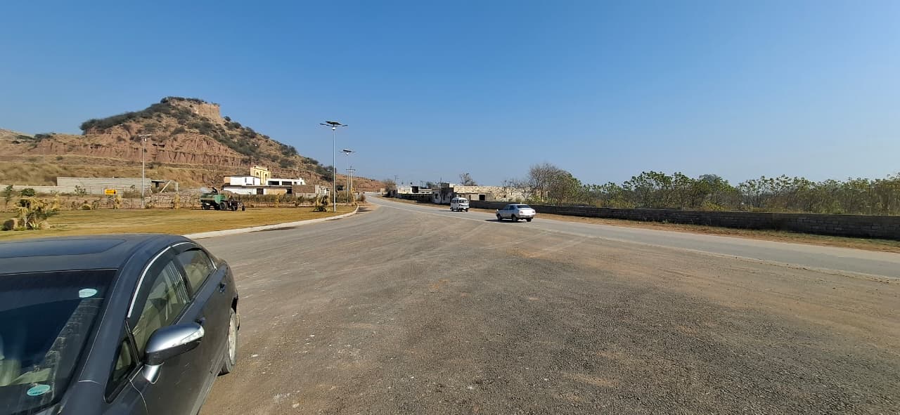 Paved road, streetlights and adjoining hillside in DHA River View South